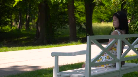 Slow-reveal-of-Japanese-girl-sitting-on-park-bench-in-summer-dress