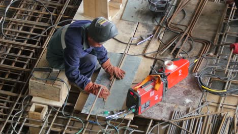 A-iron-worker-prepares-steel-rebar-for-welding-on-a-industrial-construction-site