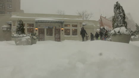 People-Walking-in-Front-of-a-Subway-Station-during-a-snowstorm-in-Brooklyn,-NY