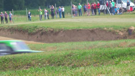 Autocross-cars-passing-by-in-amateur-racing-on-the-dirt-track,-medium-shot-over-the-grass