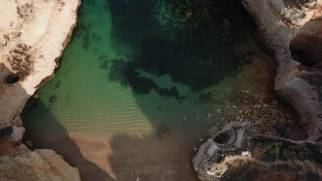 Erhebt-Sich-über-Der-Strandbucht-Der-Algarve,-Während-Klares-Meerwasser-An-Land-Gespült-Wird,-Portugal,-Vogelperspektive