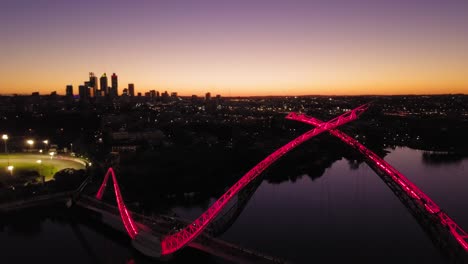 Aerial-shot-of-a-Perth-Skyline,-view-from-above-the-Swan-river-with-camera-going-from-right-to-the-left,-around-the-Matagarup-Bridge,-revealing-stadium-as-the-sun-sets