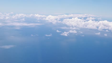 A-shot-of-the-beautiful-blue-sky-and-puffy-white-clouds-passing-by-at-10,000-feet