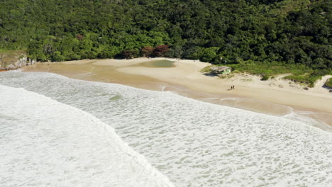Aerial-view-of-a-couple-walking-on-the-beach,-Lagoinha-Do-Leste,-Florianopolis,-Santa-Catarina,-Brazil