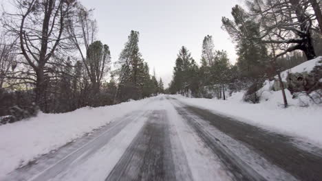 Driving-down-a-snowy-road-path-trail-fast-motion-in-the-mountains-first-person-pov