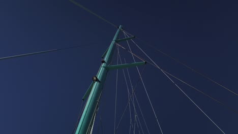 A-shot-from-below-the-mast-of-a-catamaran-with-the-main-sail-lowered-and-many-stringg-going-to-the-top