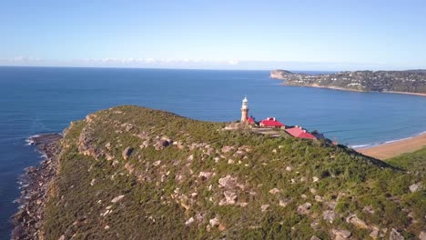 Beautiful-Island-with-a-hill-top-lighthouse-with-view-of-two-beaches-and-ocean-aerial-shot-on-a-clear-sunny-day