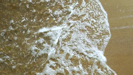 Slow-motion,-View-of-the-sea-shore,-Foam-from-water-poured-into-the-sand,-sand-and-water-on-the-coast
