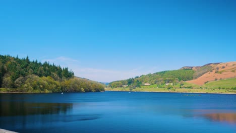Lady-Bower-Reservoir,-Wunderschöne-Landschaft,-Wald-Im-Hintergrund-Auf-Der-Linken-Seite-Und-Berge-Auf-Der-Rechten-Seite,-Peak-District,-Klarer-Himmel,-Sonniger-Tag,-Aufnahme-In-4K