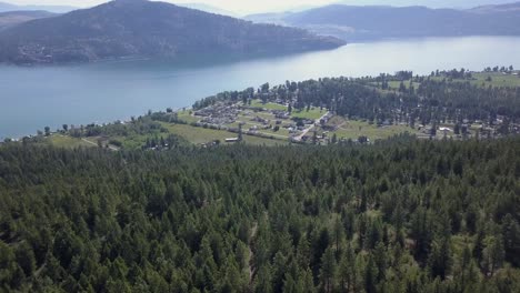 Aerial-view-over-forested-ridge-shows-small-lake-side-community