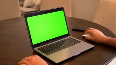 Mann-Benutzt-Laptop-Mit-Mobiltelefon-Im-Hintergrund,-Grüner-Bildschirm