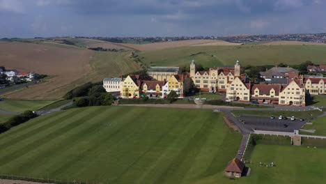 Wide-aerial-panning-view-of-Roedean-School,-situated-on-the-Chalk-cliffs-near-Brighton,-UK-to-reveal-Roedean-village-and-the-A259-coast-road
