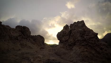 Time-lapse-of-golden-clouds-swirling-above-mountain-rocks