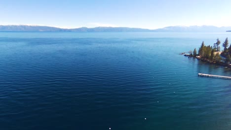Aerial-panoramic-shot-of-lake-tahoe-along-with-grees-trees-and-snow-on-a-sunny-day