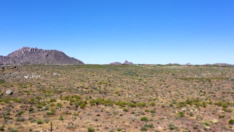 Aerial-slow-approach-across-the-open-desert-of-the-McDowell-Mountain-Preserve-to-the-rocky-hills-and-mountains-to-the-North,-Scottsdale,-Arizona