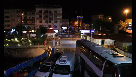 Big-cargo-ship-transporting-vehicles,-cars-and-buses,-departing-from-the-pier-in-Eceabat-Turkey-at-night