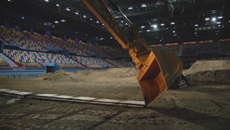 Large-earthmoving-machine-lifting-part-of-an-indoor-dirt-track