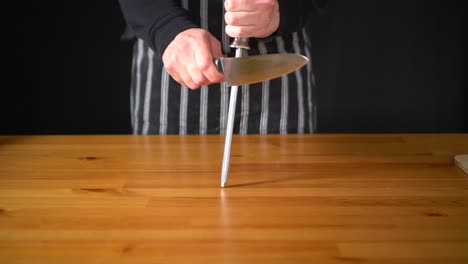 Slow-motion-of-a-man-Chef-using-various-techniques-to-sharpen-a-knife-with-his-hands,-using-a-professional-knife-and-a-diamond-sharpening-steel