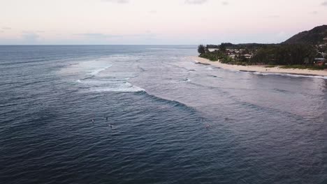 Drone-shot-flying-over-surfers-enjoying-the-waves-off-of-the-North-Shore-coast-of-Oahu,-Hawaii