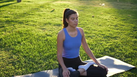 A-fit-young-woman-sitting-in-lotus-position-meditating-in-the-park-at-sunrise-to-improve-her-mental-health-and-relax