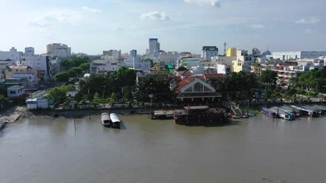 The-city-of-Can-Tho,-Vietnam-featuring-boats,-river,-and-architecture-from-drone-on-a-sunny-afternoon