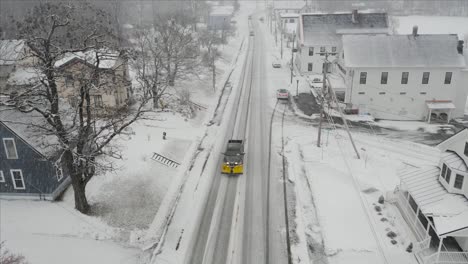 Snowplow-driving-down-road-snowstorm-aerial