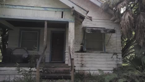 Old-grungy-vintage-house-with-overgrown-yard,-zooming-in-and-sliding-left