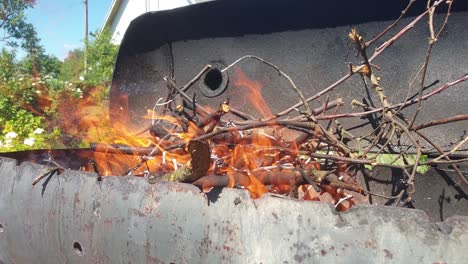 Burning-branches-in-barbecue-while-fire-is-being-blown-by-breeze
