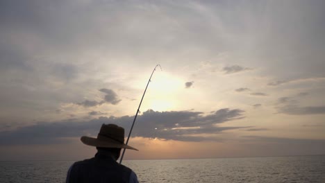 Hombre-Pescando-En-La-Costa-Dorada-Del-Atardecer-Del-Océano