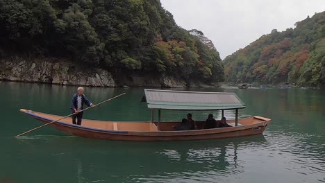 Japanese-boatman-poles-tour-boat-on-historic-Katsura-River,-Arashiyama