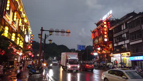 Wulingyuan,-China---Agosto-De-2019:-Vida-Bulliciosa-Con-Automóviles,-Tráfico-Y-Luces-En-Edificios-Iluminados-Por-La-Noche-En-Una-Concurrida-Calle-Principal-De-La-Ciudad-Al-Atardecer