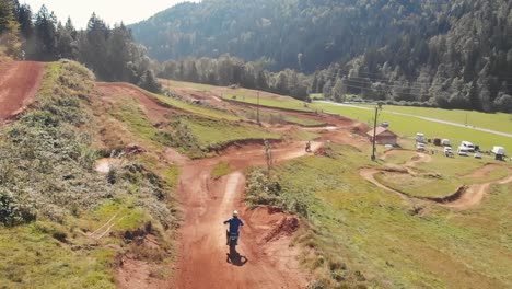 Drone-following-a-racer-on-a-dirt-bike-riding-a-motocross-track-over-the-jumps-in-slow-motion