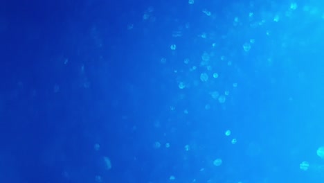 Tiefblaue-Ozeanfarbe-Mit-Wirbelndem-Glitzer-Und-Blasen,-Die-Flackern-Und-Lichtimpulse-Abgeben,-Wenn-Sie-Sich-Bewegen,-Großer-Beruhigender-Hintergrund