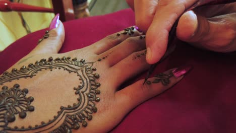 close-up-shot-of-an-elegant-and-manicured-womans-hand-with-pink-nails-receiving-a-traditional-henna-tattoo-in-little-india-in-Singapore
