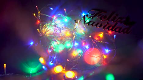 Beautiful-colored-LED-lights-draw-cycles-on-the-image-while-a-hand-places-and-removes-a-sign-in-which-you-can-read-Merry-Christmas-in-Spanish