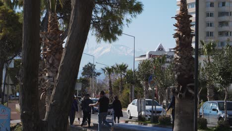 Medium-shot,-man-carries-his-daughter-on-the-side-of-the-street,-people-walking-around-in-Antalya