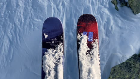 A-pair-of-red-and-blue-skis-hanging-on-a-ski-lift,-pure-white-snow-moving-in-the-background
