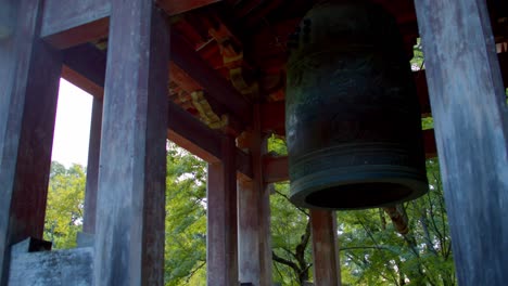 Close-up-shot-of-a-big-Japanses-bell-low-angle,-in-japanses-garden-in-the-background-in-Kyoto,-Japan-soft-lighting-4K