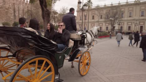 Tourists-ride-in-horse-drawn-carriage-in-Seville,-Spain,-Tracking-Pan