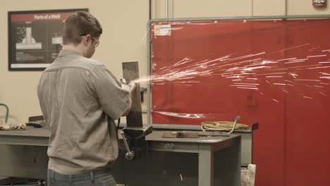 Trade-school-student-uses-a-grinding-tool-to-polish-a-piece-of-steel-with-sparks-flying