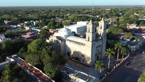 Aerial-trucking-shot-to-left-showing-Cathedral-de-San-Gervasio-and-the-city-beyond-after-sunrise-in-Valladolid,-Yucatan,-Mexico