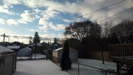 daytime-winter-time-lapse-looking-out-through-a-window-to-a-Canadian-backyard,-panning-to-the-right-and-up-into-the-sky,-featuring-fast-moving-clouds-and-rapidly-shifting-light