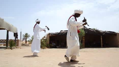 Two-Berberes-playing-tradicional-music-and-dancing-in-the-Sahara-Desert,-Morocco