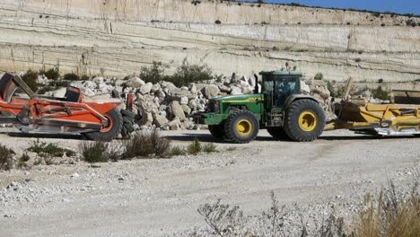 John-Deere-Traktor-Schleppt-Orangefarbenes-Erdbewegungsgerät-Auf-Einer-Baustelle-In-Der-Nähe-Von-Torrevieja,-Spanien