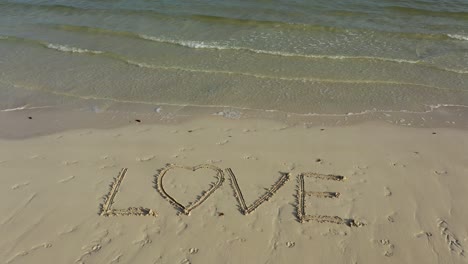 Static-shot-of-LOVE-inscribed-in-the-sand-on-a-beach