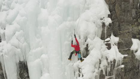 Single-climber-on-frozen-ice-cascade-preparing-safety-line-4K