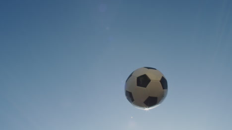 Slow-motion-medium-shot-of-a-soccer-ball-as-it-arcs-through-the-scene