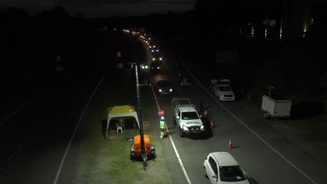 Cars-Driving-At-Night-From-NSW-To-Gold-Coast-Border-In-Queensland,-Australia---Traffic-At-Border-Checkpoint---Coronavirus-Pandemic---wide-shot