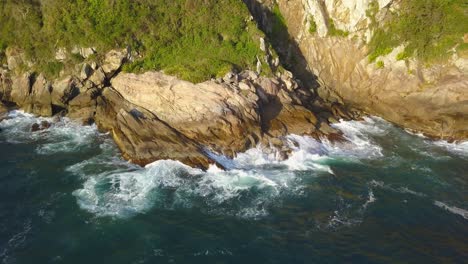 Aerial-parallax-shot-of-the-rugged-coastline-on-the-Trilha-da-Sepultura-at-golden-hour-in-Bombinhas