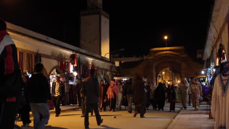 Vista-De-La-Calle-De-Hombres-Y-Mujeres-Locales-Comprando-En-Essaouira,-Marruecos-Por-La-Noche